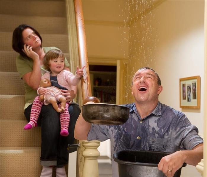 A man and his family catching water falling from above in pots 