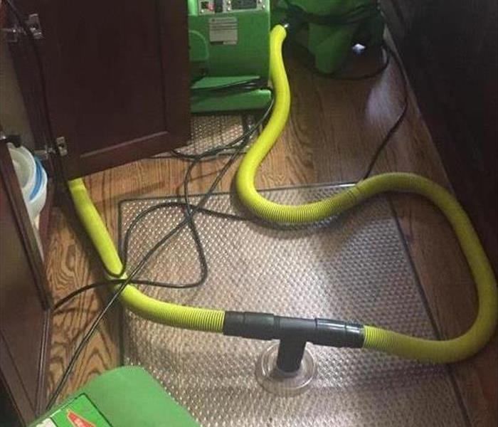 Drying equipment with a plastic mat to suction moisture from a hardwood floor